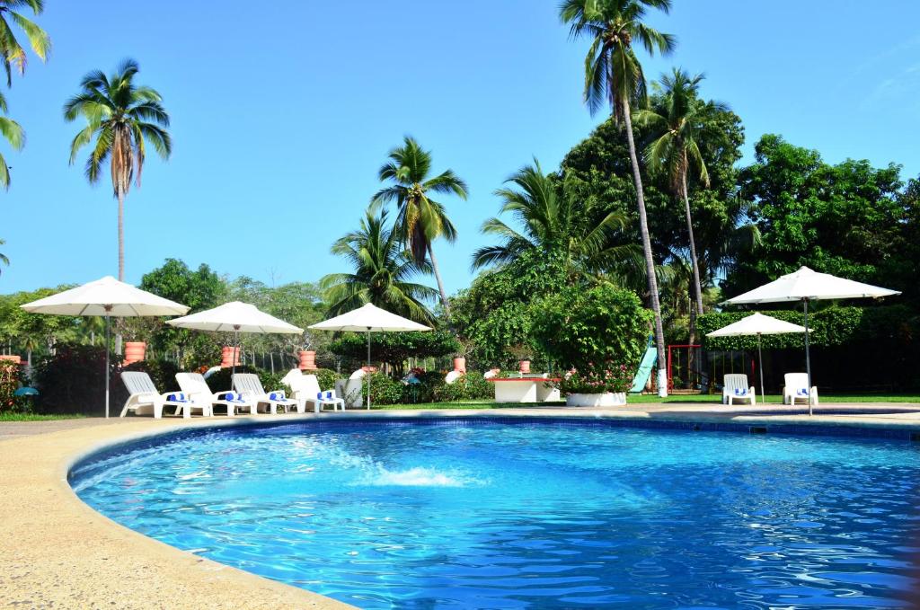 una piscina con sillas y sombrillas en Coral Ixtapa en Ixtapa