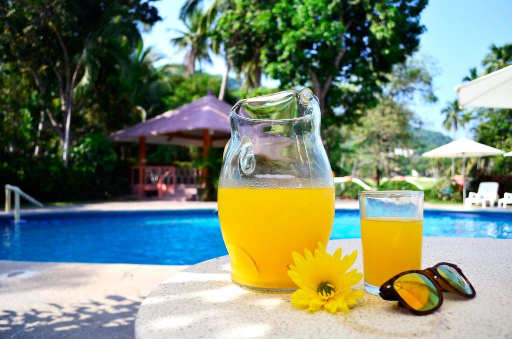 a glass of orange juice next to a glass of sunglasses and a flower at Coral Ixtapa in Ixtapa