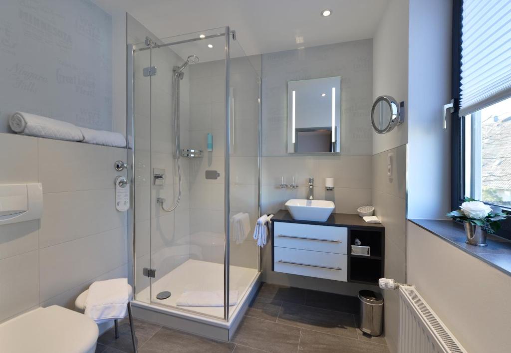 a bathroom with a glass shower and a sink at Hotel Spiegel in Cologne