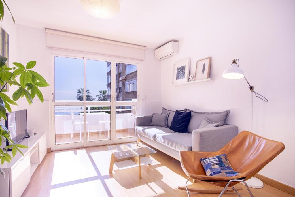 sala de estar con sofá y ventana grande en Malagueta Blue en Málaga