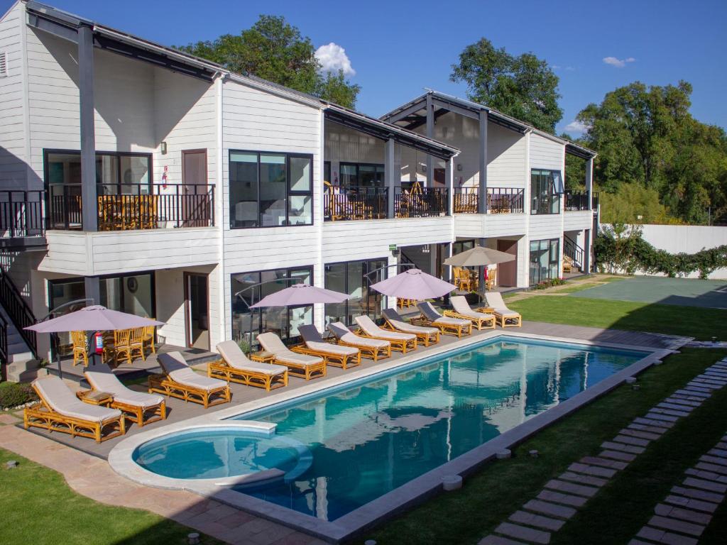 阿特利斯科的住宿－Grand Gardenia，酒店设有带椅子和遮阳伞的游泳池