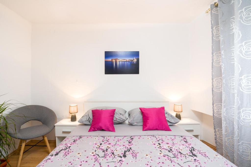 a bedroom with a bed with pink pillows at Apartment Sokol in Dubrovnik
