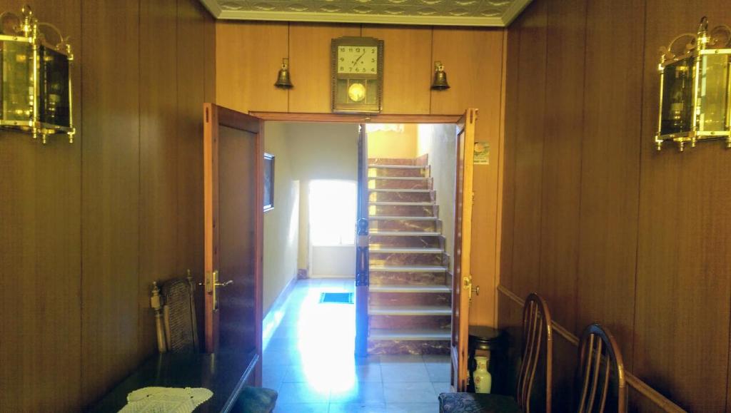 a hallway with stairs and a clock on the wall at Casa de la Riva in Trobajo del Camino