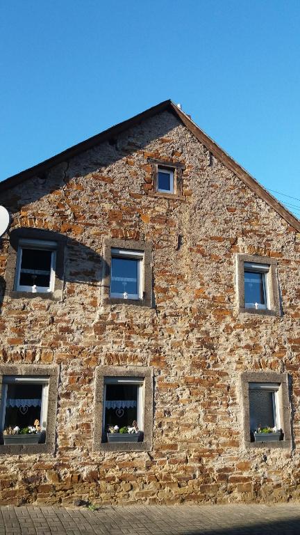 ein Backsteingebäude mit sechs Fenstern mit Blumen darin in der Unterkunft EifelverWeiler in Weiler