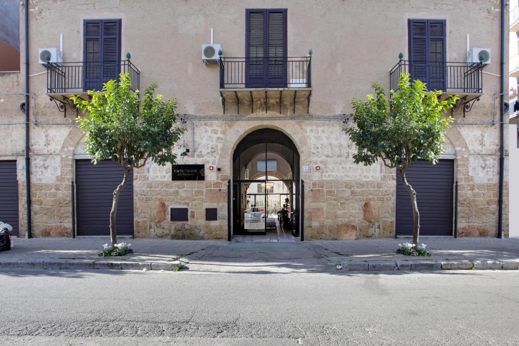 un bâtiment avec deux arbres devant une porte dans l'établissement B&B Palazzo Corselli, à Bagheria