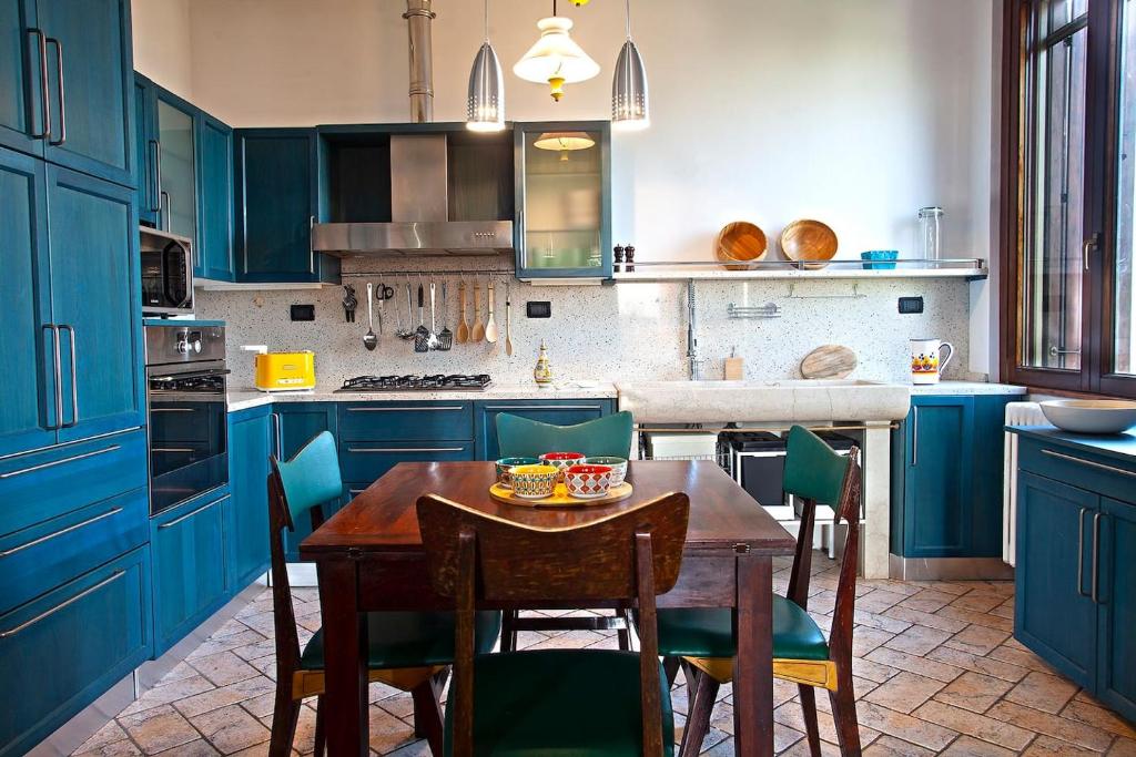 una cocina con armarios azules y una mesa con sillas en CaseOspitali - Cà del Frassino - suggestivo appartamento in villa 2 camere e 2 bagni x5, en Gorgonzola