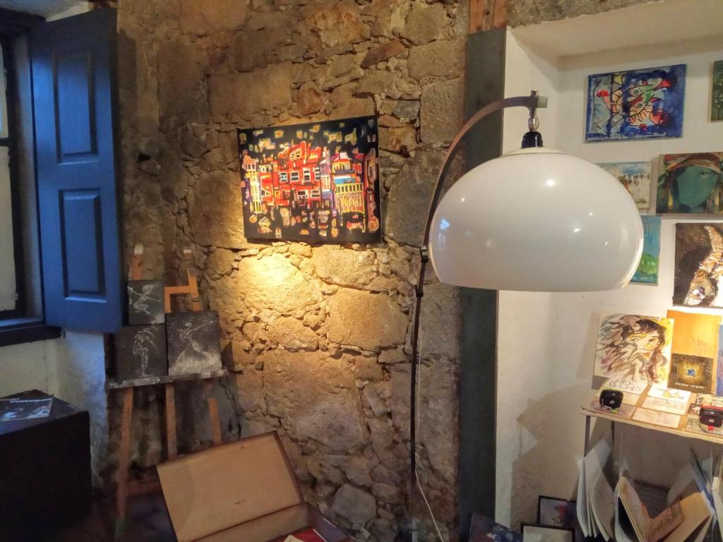 Habitación con lámpara y pared de piedra. en Dans L'Atelier Hostel en Braga