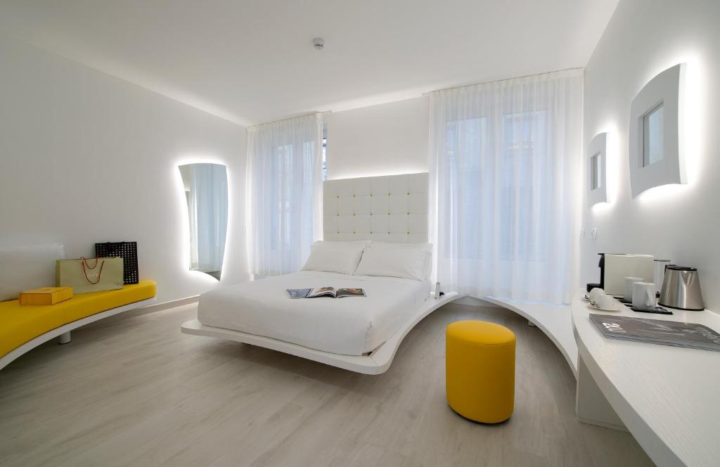 um quarto branco com uma cama branca e um banco amarelo em AHD Rooms em Milão
