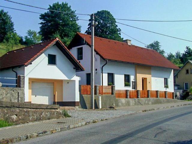 una casa blanca con techo rojo en una calle en Pension U Holzäpfelů - apartmán, en Červený Kostelec