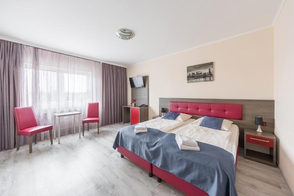 1 dormitorio con 1 cama grande y 2 sillas rojas en Hotel Klein Frankfurt, en Frankfurt