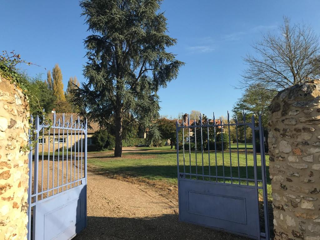 un cancello in un parco con un albero di La Bergerie du Domaine des Buissonnets a Écardenville-sur-Eure