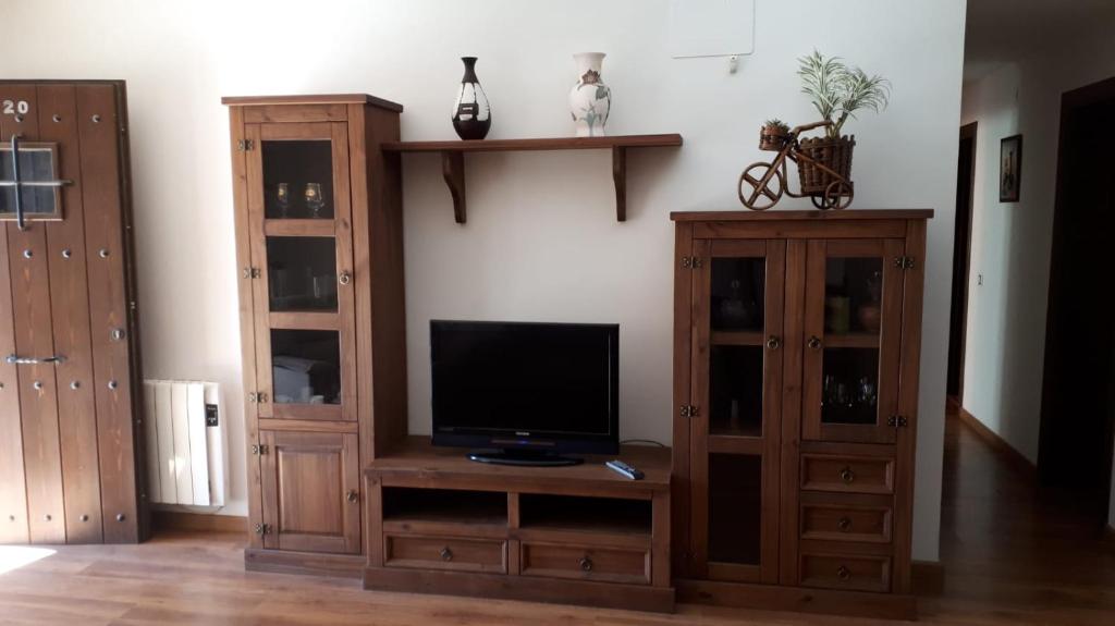 sala de estar con TV y algunos armarios de madera. en Casa Tere, en Orihuela del Tremedal