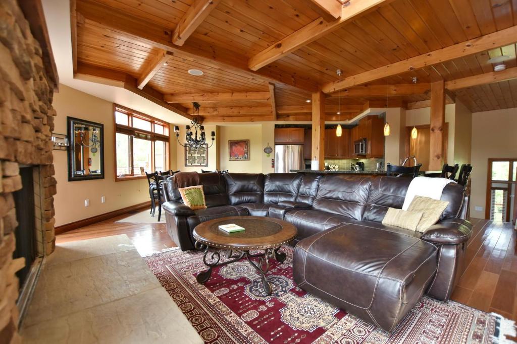 a living room with a leather couch and a table at Blue Mountain-Luxurious BlueSki George Chalet, Hot Tub, Pool, Gas Fireplace in Blue Mountains