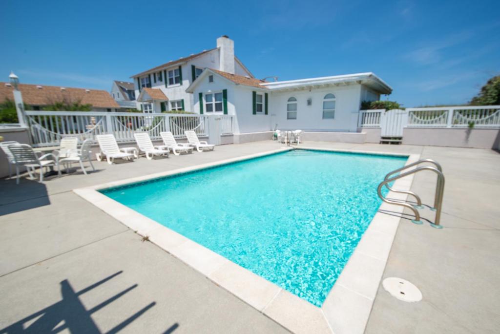 a swimming pool with chairs and a house at A Shore Thing in Southern Shores