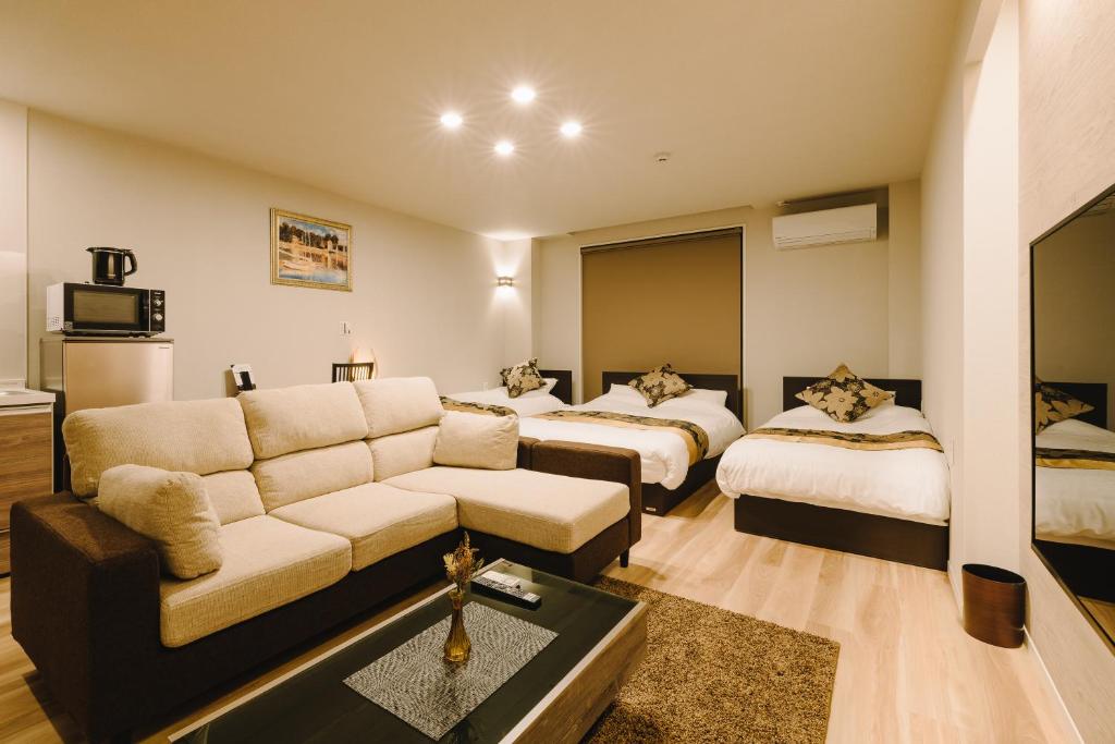 a living room with a couch and two beds at GRAND BASE Karatsu Ekiminami in Karatsu