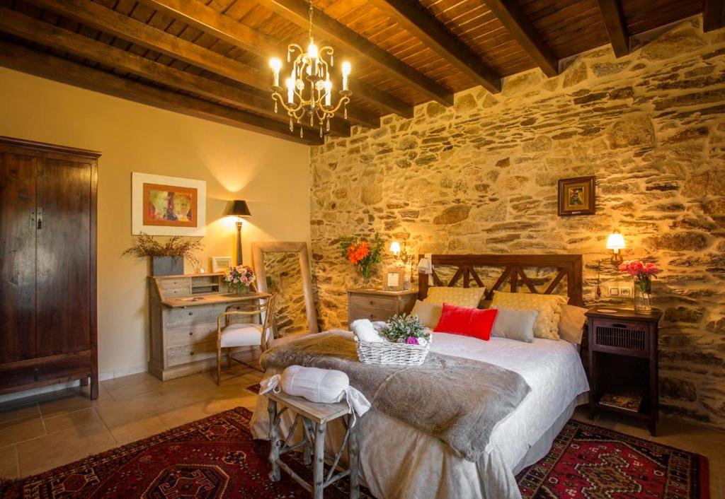 a bedroom with a large bed in a stone wall at Casa Ramiras in O Viso