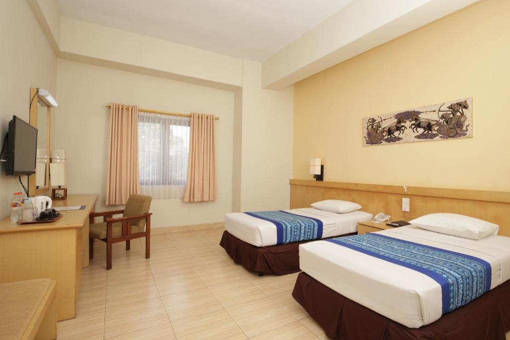 a hotel room with two beds and a desk at University Club (UC) Hotel UGM in Yogyakarta
