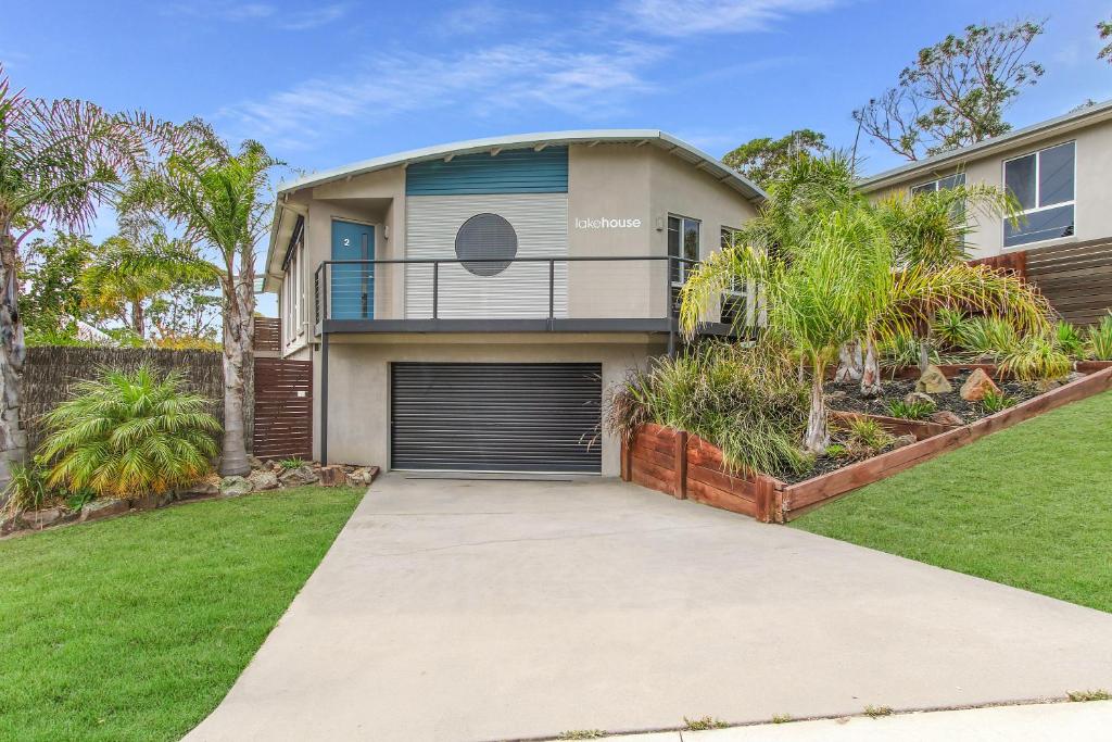 a house with a garage and palm trees at Lake House in Lake Tyers