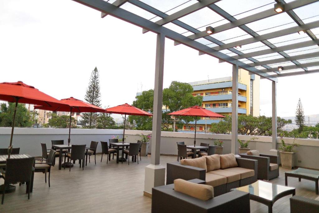 um pátio com mesas, cadeiras e guarda-sóis vermelhos em Hyatt Place Tegucigalpa em Tegucigalpa