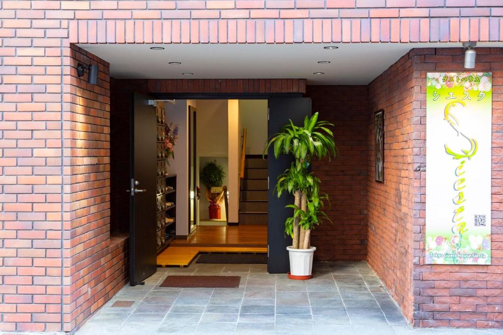 a brick building with a door and a plant in it at Guest House Siesta in Tokyo