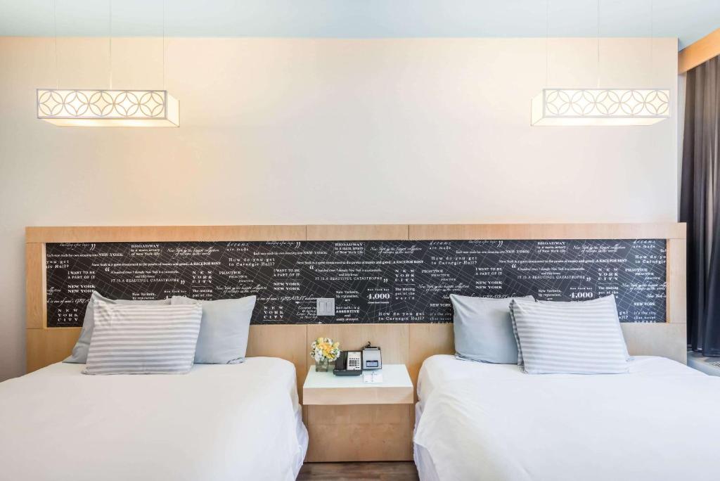 two beds in a room with a chalkboard on the wall at TRYP by Wyndham New York City Times Square - Midtown in New York