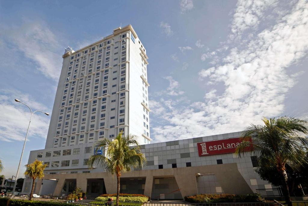 a tall white building with palm trees in front of it at TRYP by Wyndham Mall of Asia Manila in Manila