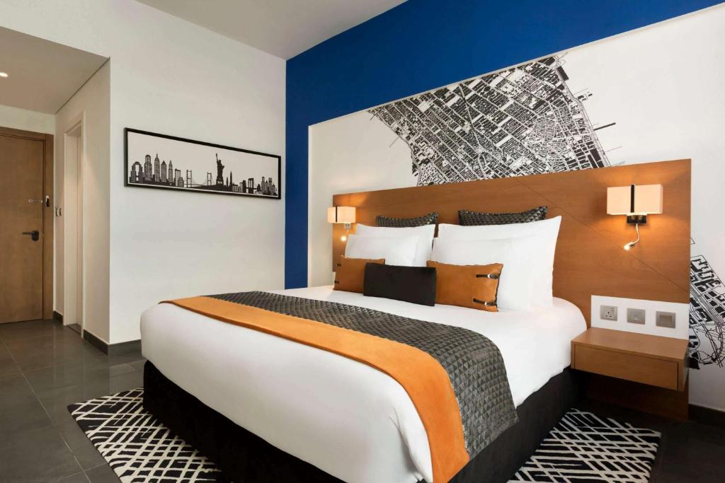 a hotel room with a large bed with blue walls at TRYP by Wyndham Dubai in Dubai