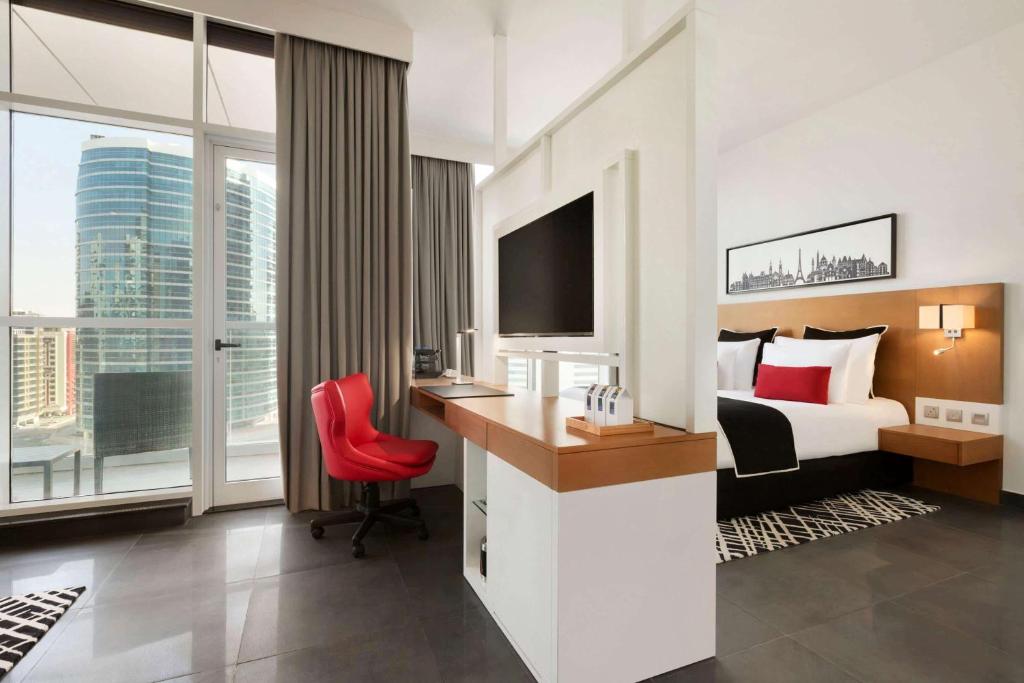 a hotel room with a bed and a desk with a computer at TRYP by Wyndham Dubai in Dubai