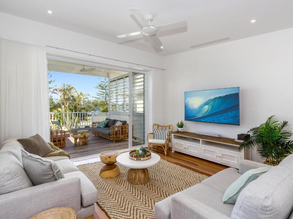 a living room with a couch and a tv at Marine Beach House in Kingscliff