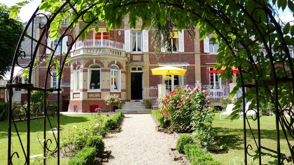 a brick house with a yellow umbrella in front of it at VILLA la GLORIETTE in Rouen
