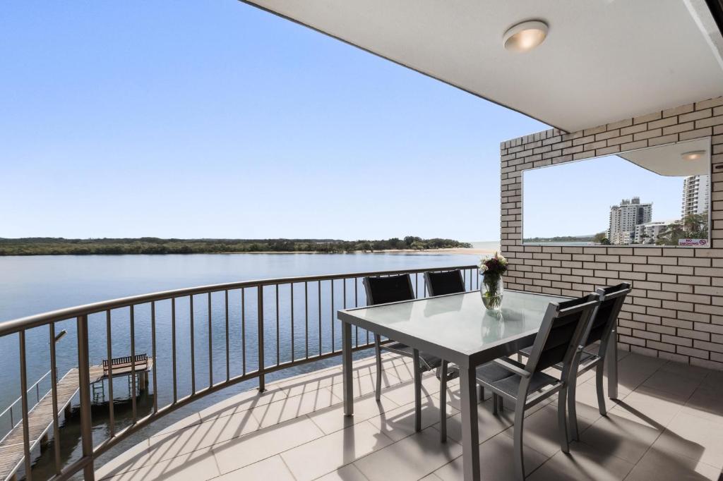 einen Balkon mit einem Tisch und Stühlen sowie Blick auf das Wasser in der Unterkunft Wharf Lodge River View Apartment in Maroochydore