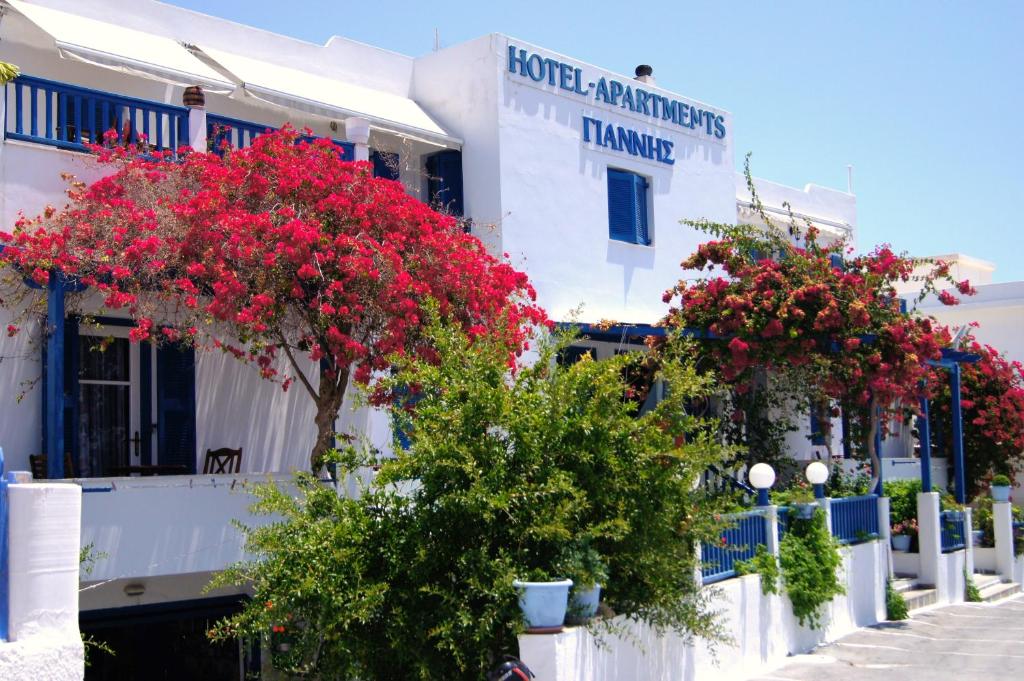 a row of white buildings with red flowers on them at Giannis Hotel Apartments in Adamantas