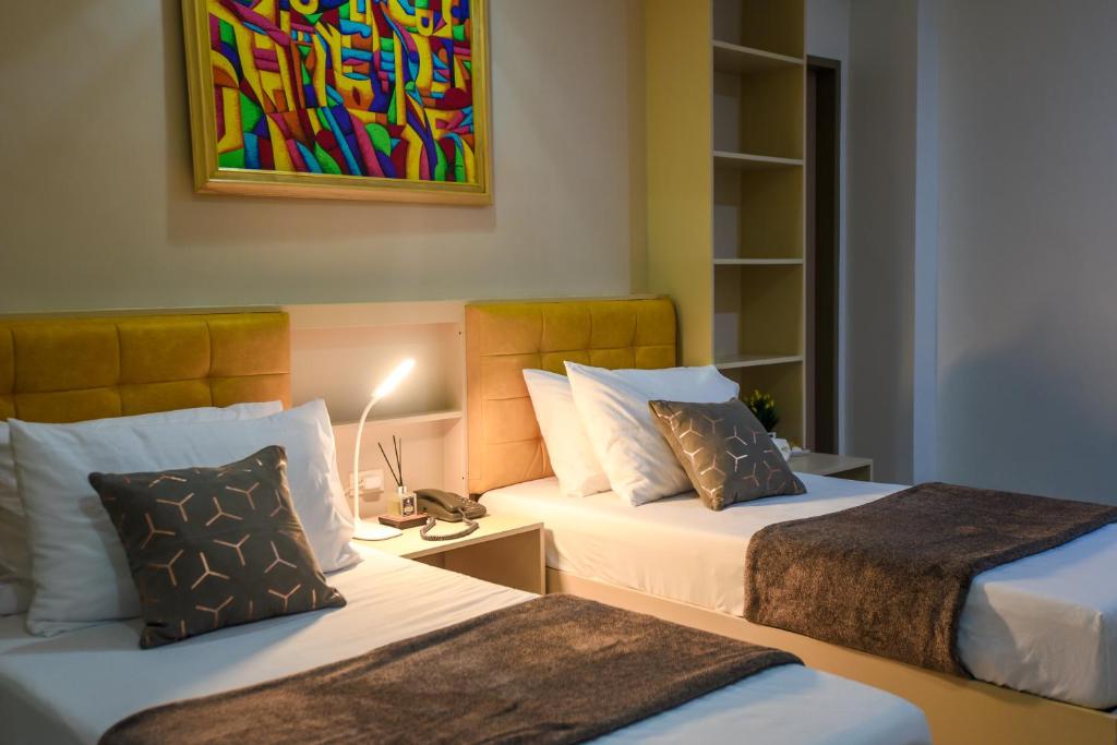 a bedroom with two beds and a painting on the wall at ETT HomeTel in Kalibo