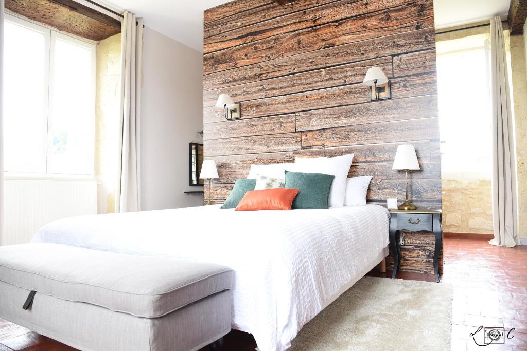 a bedroom with a white bed and a wooden wall at A CLAIREFONTAINE in Auch