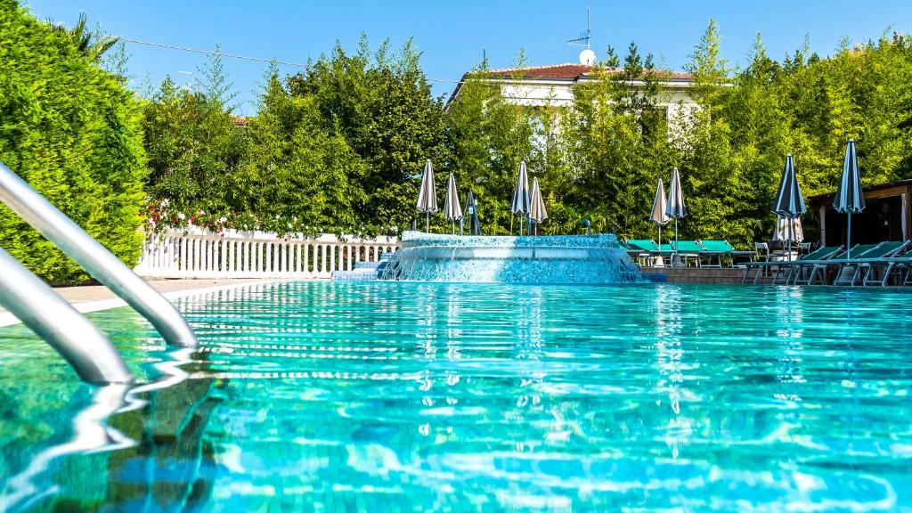 a swimming pool with blue water and blue umbrellas at Hotel Smeraldo in Lazise
