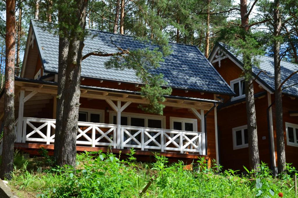 une maison dans les bois avec un toit en gambrel dans l'établissement Domki Kaszuby - jezioro las i zoo w Szarlocie, à Kościerzyna