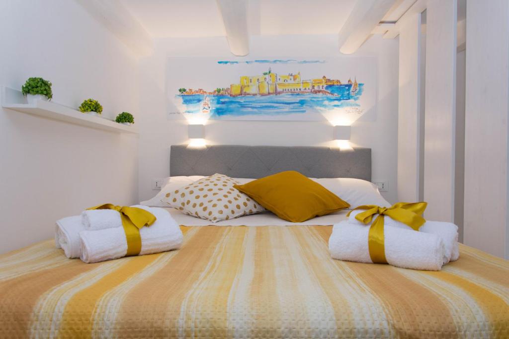 1 dormitorio con 1 cama con almohadas amarillas y blancas en Little House en Siracusa