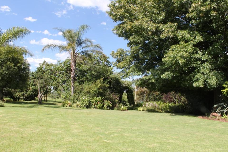 einen Park mit grünem Gras und Palmen in der Unterkunft Kismet Farm in Muldersdrift