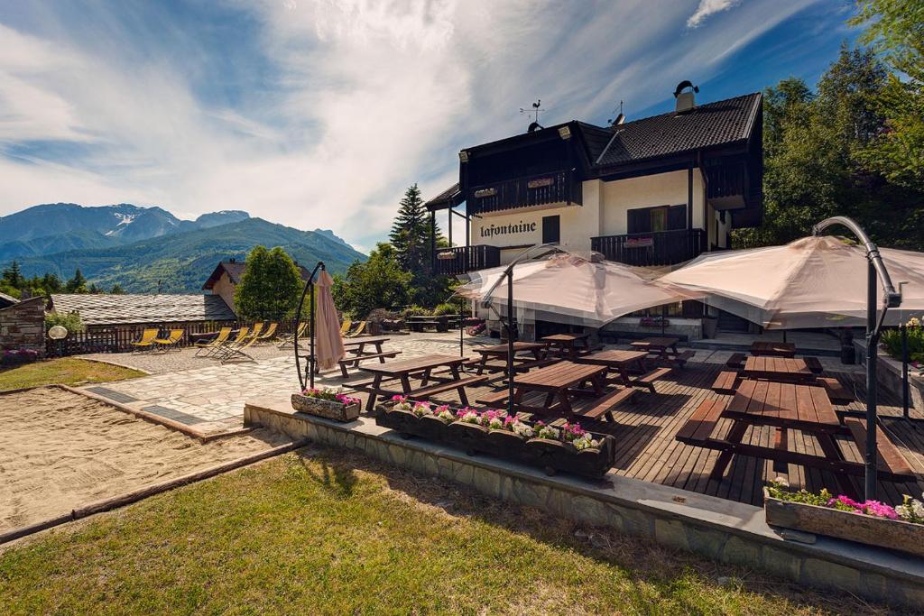 a house with a patio with tables and umbrellas at Hotel La Fontaine in Sauze dʼOulx