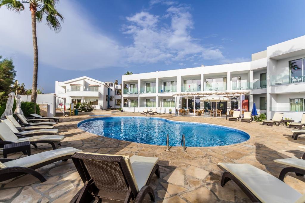 a resort with a swimming pool and chairs and a building at Bellini Hotel in Ayia Napa