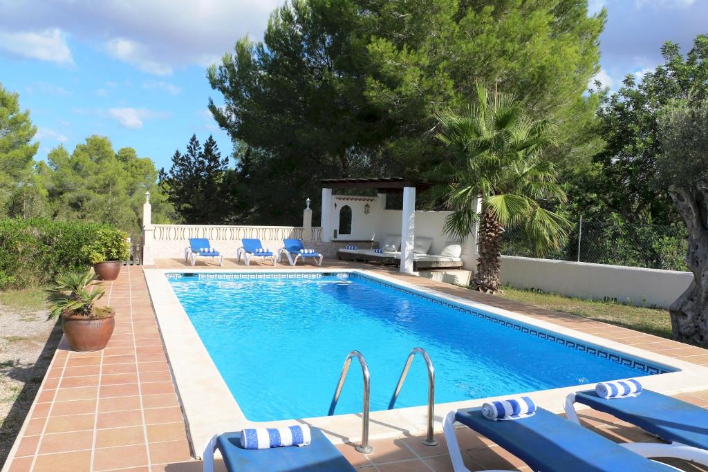 a swimming pool with blue chairs and a house at Villa Susan Ibiza in San Antonio