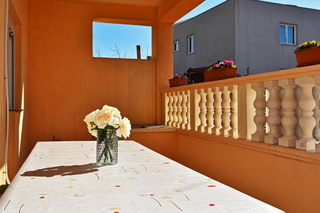 eine Vase mit Blumen auf einem Tisch auf einem Balkon in der Unterkunft Apartman Nina in Zadar