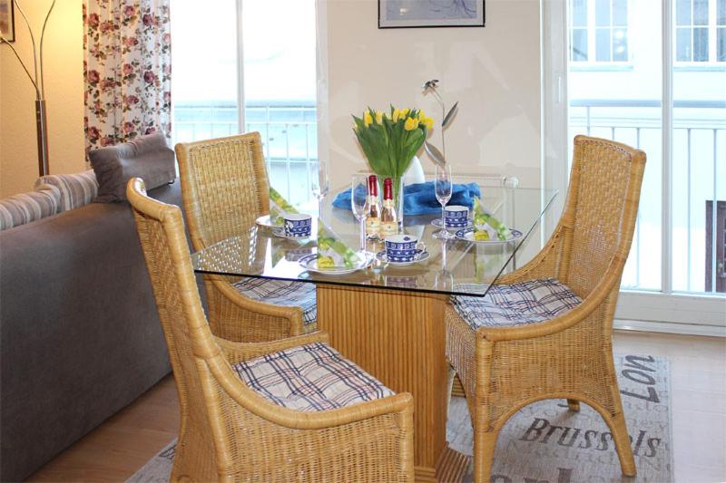 a dining table with chairs and a glass table with flowers at Appartementhaus Olymp in Kühlungsborn