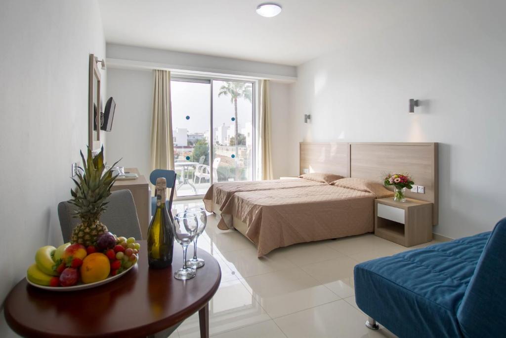 a bedroom with a bed and a table with a bowl of fruit at Bellini Hotel in Ayia Napa