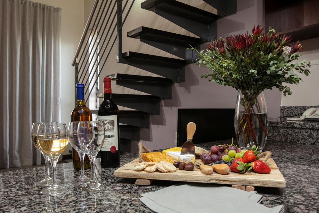 a table with wine glasses and a cutting board with food at Absolute Farenden Apartments in Pretoria