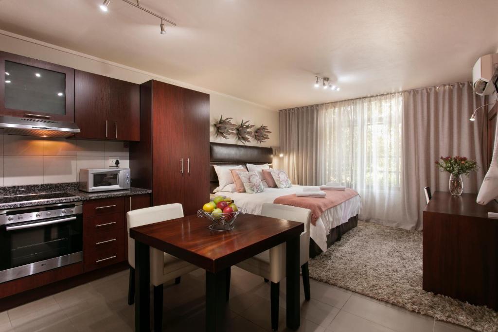 a hotel room with a bed and a table and a kitchen at Absolute Farenden Apartments in Pretoria