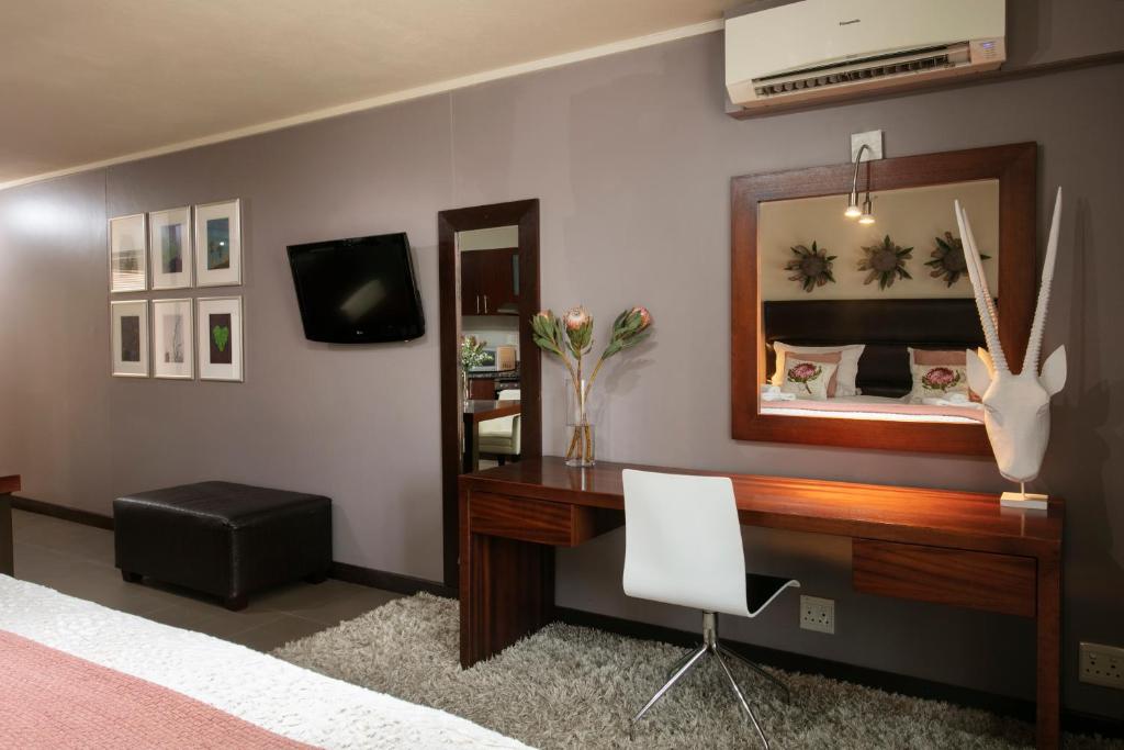 a bedroom with a desk and a mirror at Absolute Farenden Apartments in Pretoria
