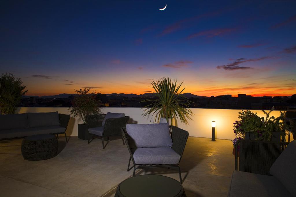 a patio with chairs and a sunset in the background at Milestone in Quartu SantʼElena