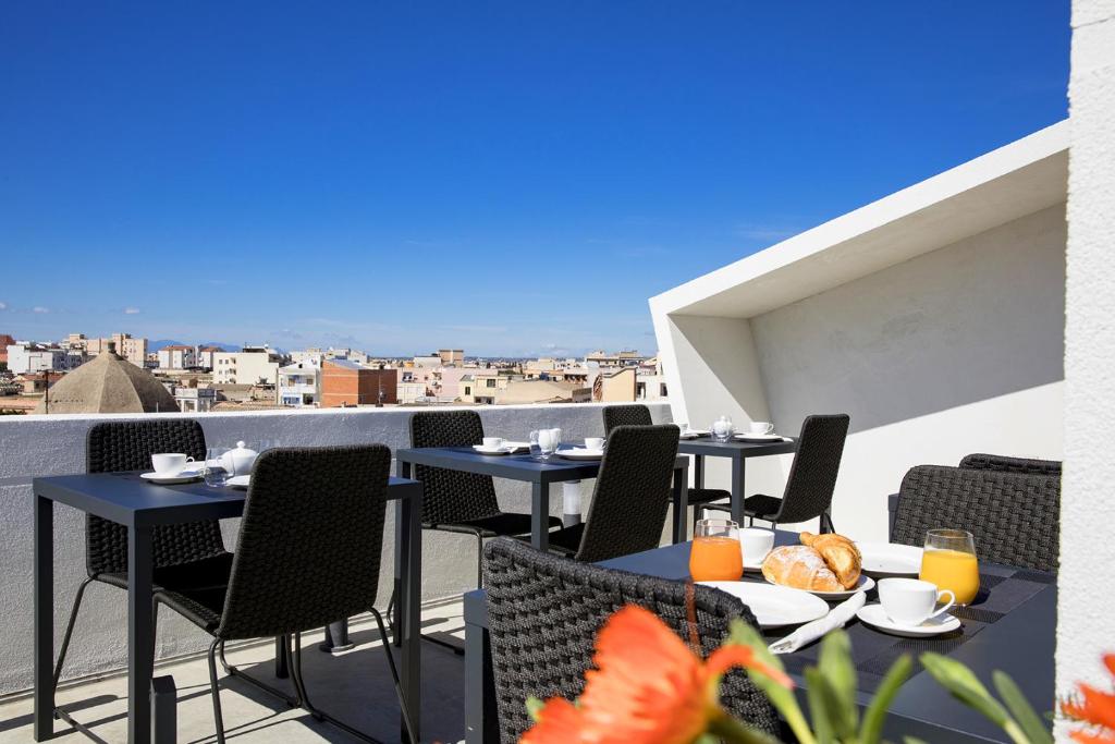a patio with tables and chairs on a balcony at Milestone in Quartu SantʼElena