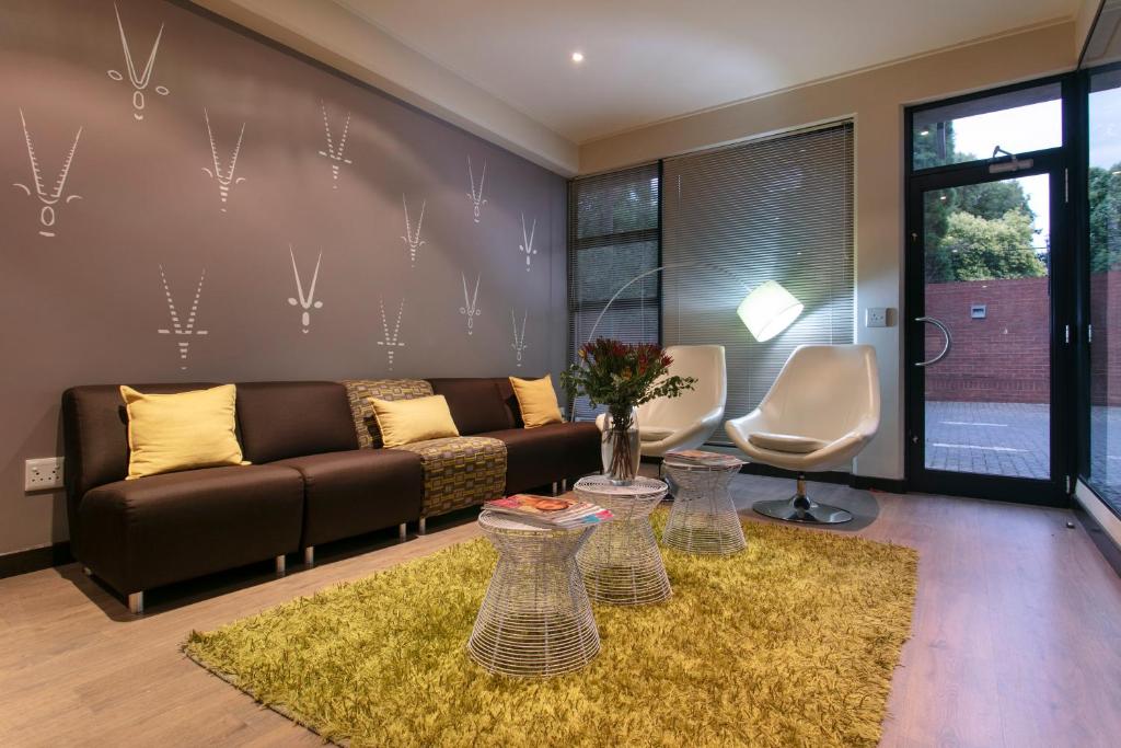 a living room with a brown couch and two chairs at Absolute Farenden Apartments in Pretoria
